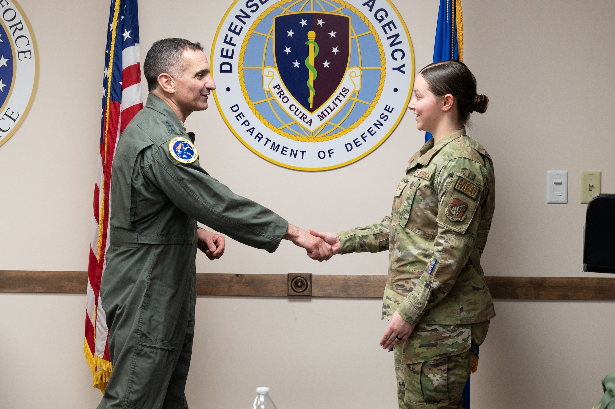 U.S. Air Force Lt. Gen. David Nahom, commander, Alaskan NORAD Region, Alaskan Command and Eleventh Air Force, gives a coin to Senior Airman Evelynn Perry, 354th Medical Group commander support staff, during a base visit at Eielson Air Force Base, Alaska, Feb. 1, 2024.