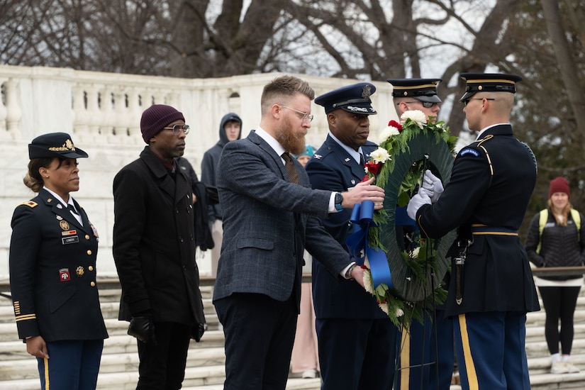 A group of people setting up a wreath at a tomb.