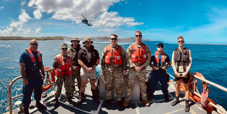 U.S. Army Scouts stand for a photo with U.S. Coast Guard members with a U.S. Navy Helicopter Sea Combat Squadron 25 MH-60S Knighthawk helicopter over Apra Harbor, Guam, on Feb. 1, 2024. In a demonstration of inter-service cooperation and expertise, the crew of the U.S. Coast Guard Station Apra Harbor's 45-foot Response Boat-Medium supported an intricate cast and recovery training exercise. This vital training involved collaboration with the U.S. Army Scouts from the 3rd Squadron, 4th U.S. Cavalry Raiders of the 3rd Infantry Brigade Combat Team (IBCT), 25th Infantry Division, and the U.S. Navy Helicopter Sea Combat Squadron 25 - the "Island Knights," based at Andersen Air Force Base. (U.S. Coast Guard photo by Josiah Moss)