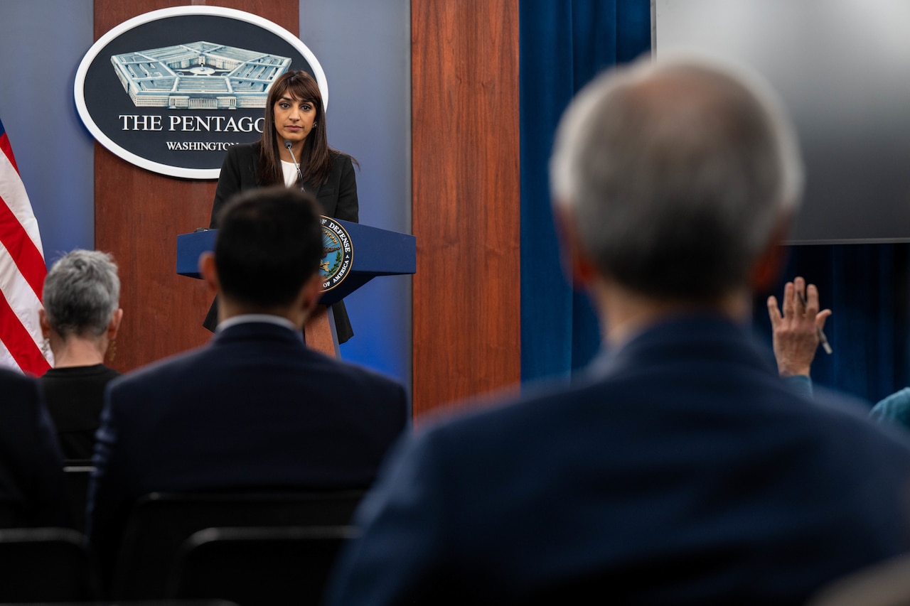A woman stands behind a lectern. The sign behind her indicates that she is at the Pentagon in Washington.