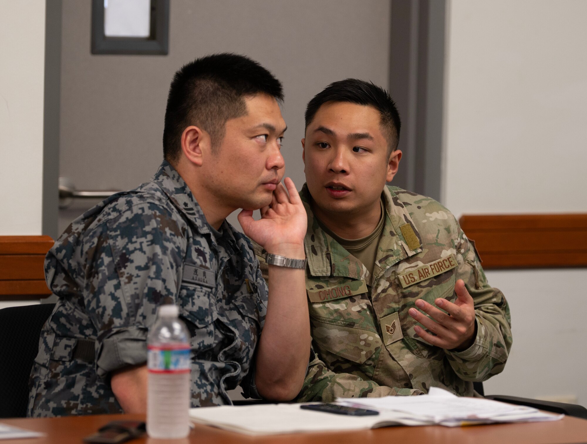 Japan Air Self Defense Force pilot Maj. Satoshi Asaoka, Air Staff Office Operations Division, is listening to U.S. Air Force Staff Sgt. Kelvin Chong, Patrolman of Kadena Air Base 18th Security Forces Squadron, translate what the other leaders are saying during one of the Security Forces Key Leadership Engagement meetings at Andersen Air Force Base, Guam, Jan. 30, 2024. The purpose of the KLE meeting is to enhance interpersonal relationships among attendees, and 
provide networking opportunities for multilateral partnerships and allies. (U.S. Air Force photo by Airman 1st Class Audree Campbell)