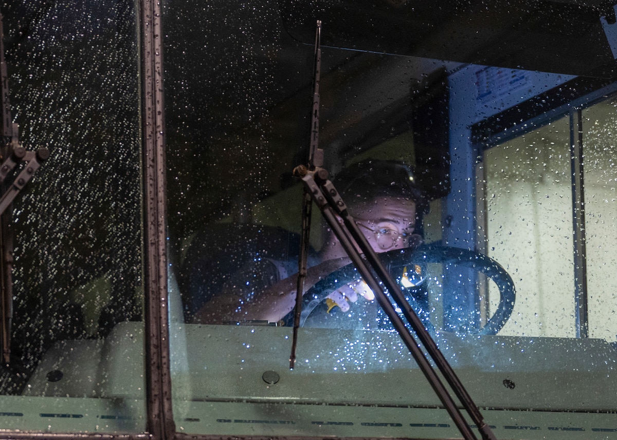 USAF Senior Airman uses a light to evaluate a seemingly inoperable vehicle during a training exercise.