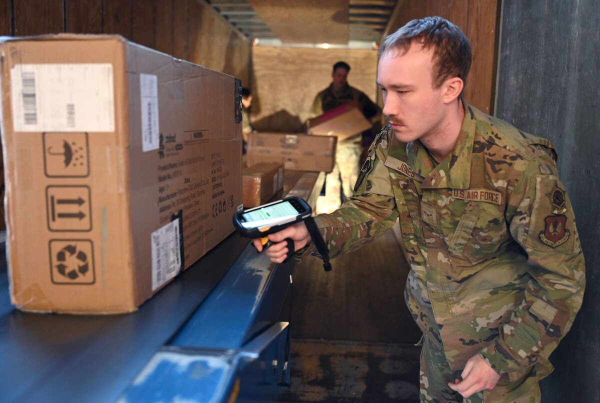 U.S. Air Force Airman 1st Class Michael Jones, 100th Force Support Squadron military postal clerk, scans incoming packages as they come off a secure truck, ensuring they are registered on the U.S. Postal Service tracking system before being made ready for customers at Royal Air Force Mildenhall, England, Feb. 2, 2024. The 100th Air Refueling Wing command team visited the post office for an immersion to see for themselves the process which allows Team Mildenhall customers to receive and send mail. (U.S. Air Force photo by Karen Abeyasekere)