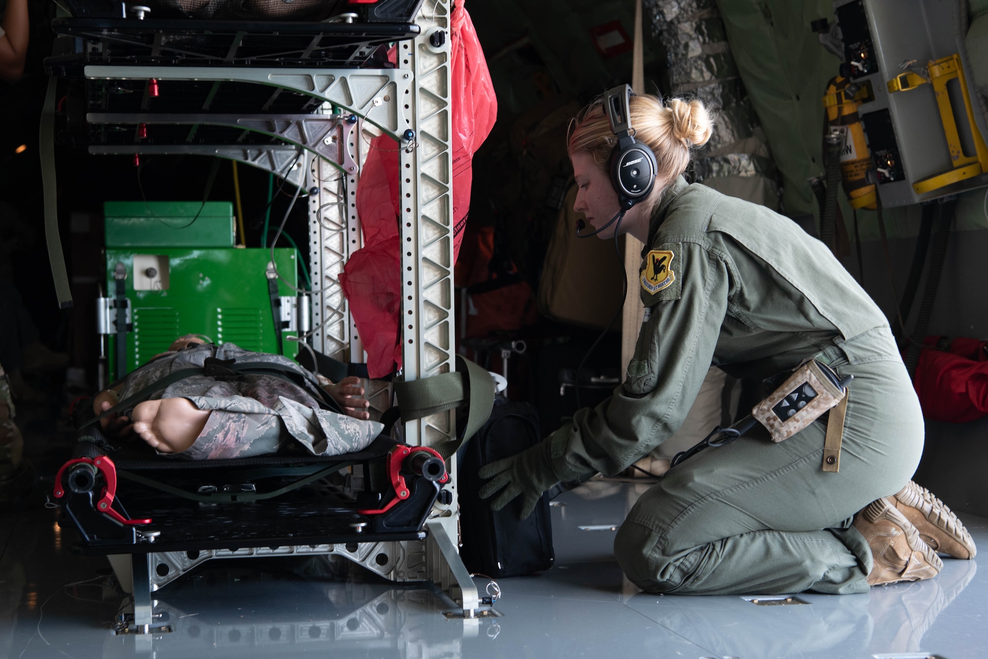 medical airman kneels next to a manikin