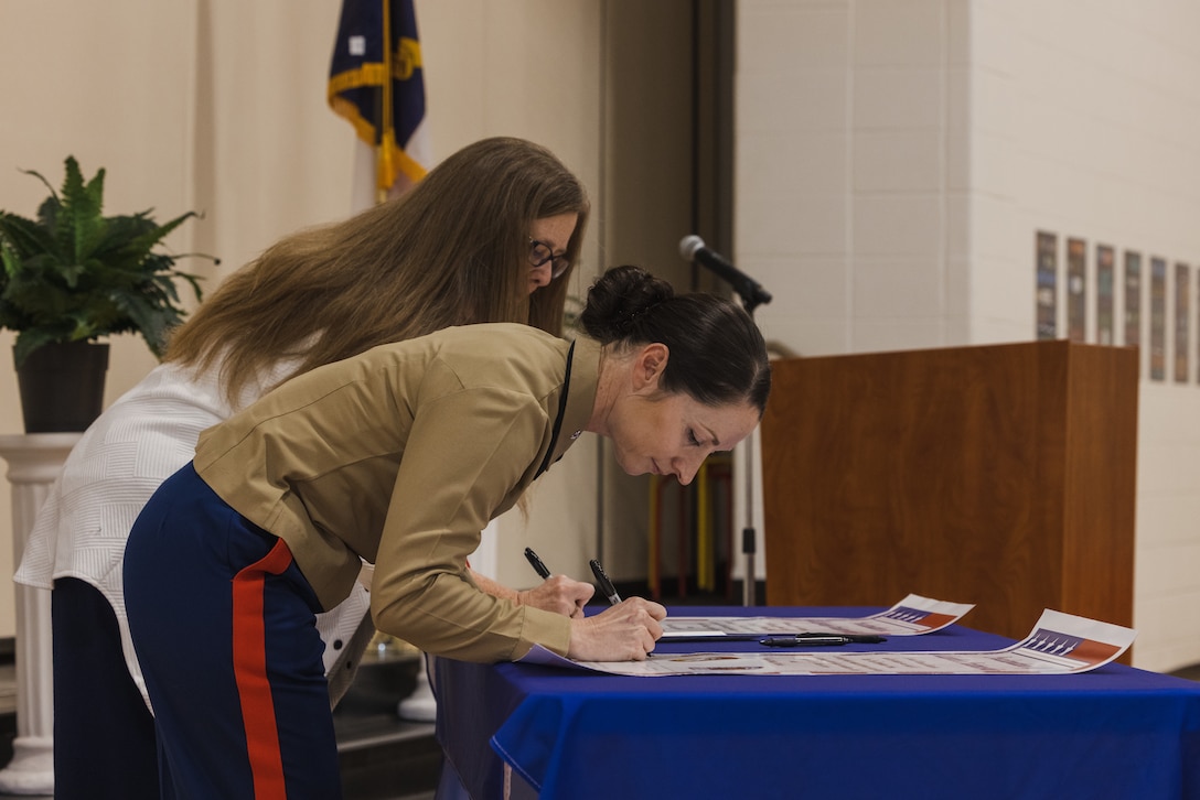 U.S. Marine Corps Lt. Col. Laura J. Perazzola-Ash, commanding officer, Wounded Warrior Battalion-East (WWBn-E), signs the proclamation of adoption partnership during the Adopt-a-School ceremony on Feb. 5, 2024 at Clear View Elementary School in Jacksonville, North Carolina. The Adopt-a-School program gives a military unit the ability to support local schools by assisting with field trips, family nights, Month of the Military Child and other special events. (U.S. Marine Corps photo by Cpl. Jennifer E. Douds)