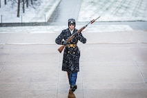 U.S. Army soldier in cold weather uniform wearing sunglassing with rifle in hands marching in snowy conditions