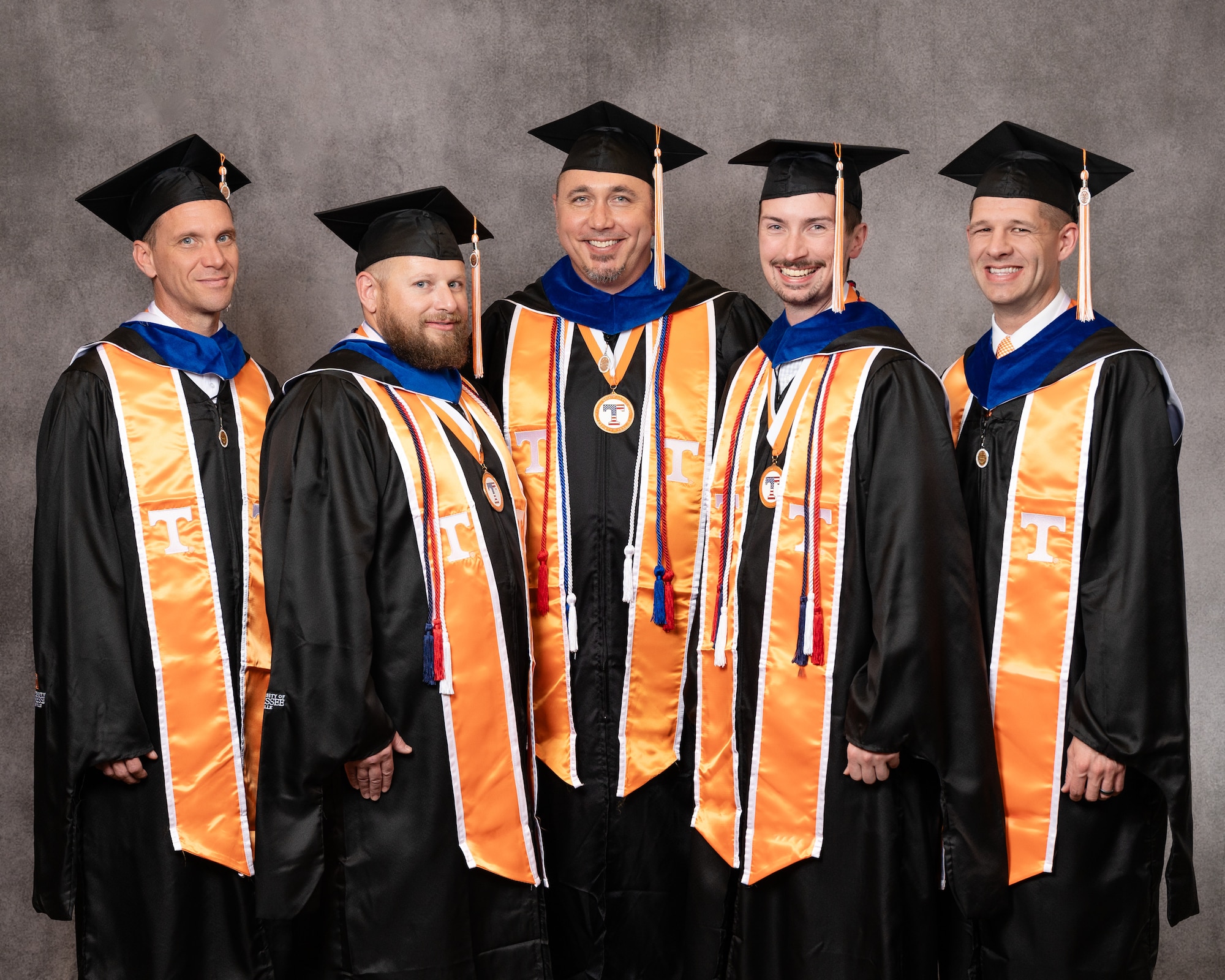 Five Ogden Air Logistics Complex employees pose in cap and gown upon earning their MBA degrees