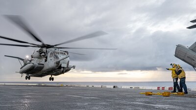 Sailors signal a helicopter aboard USS Somerset (LPD 25) in the Pacific Ocean.