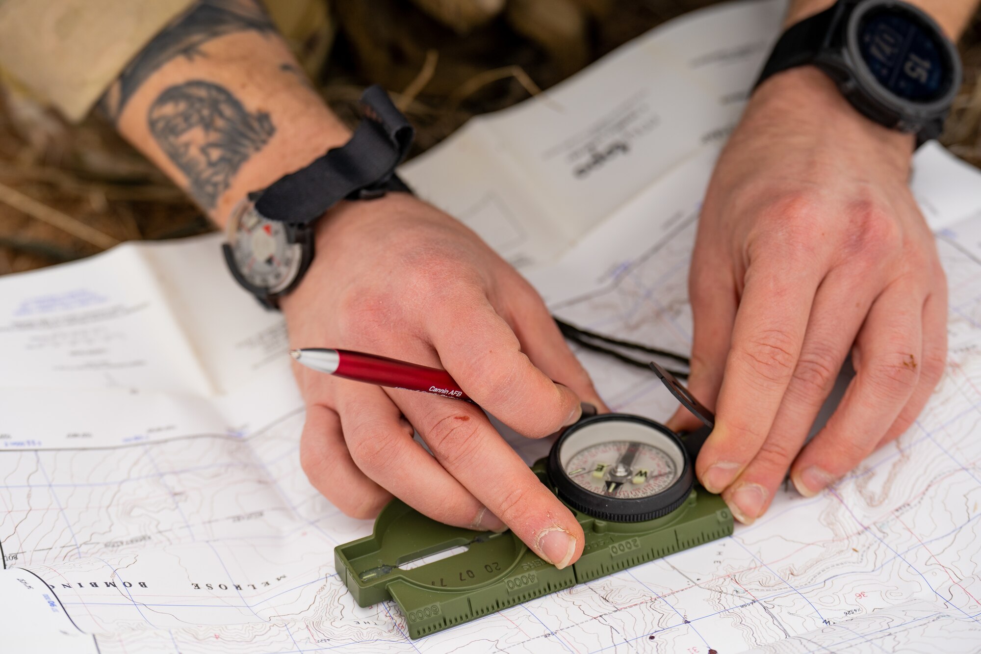 A man's hands hold a compass and pen on top of a map.