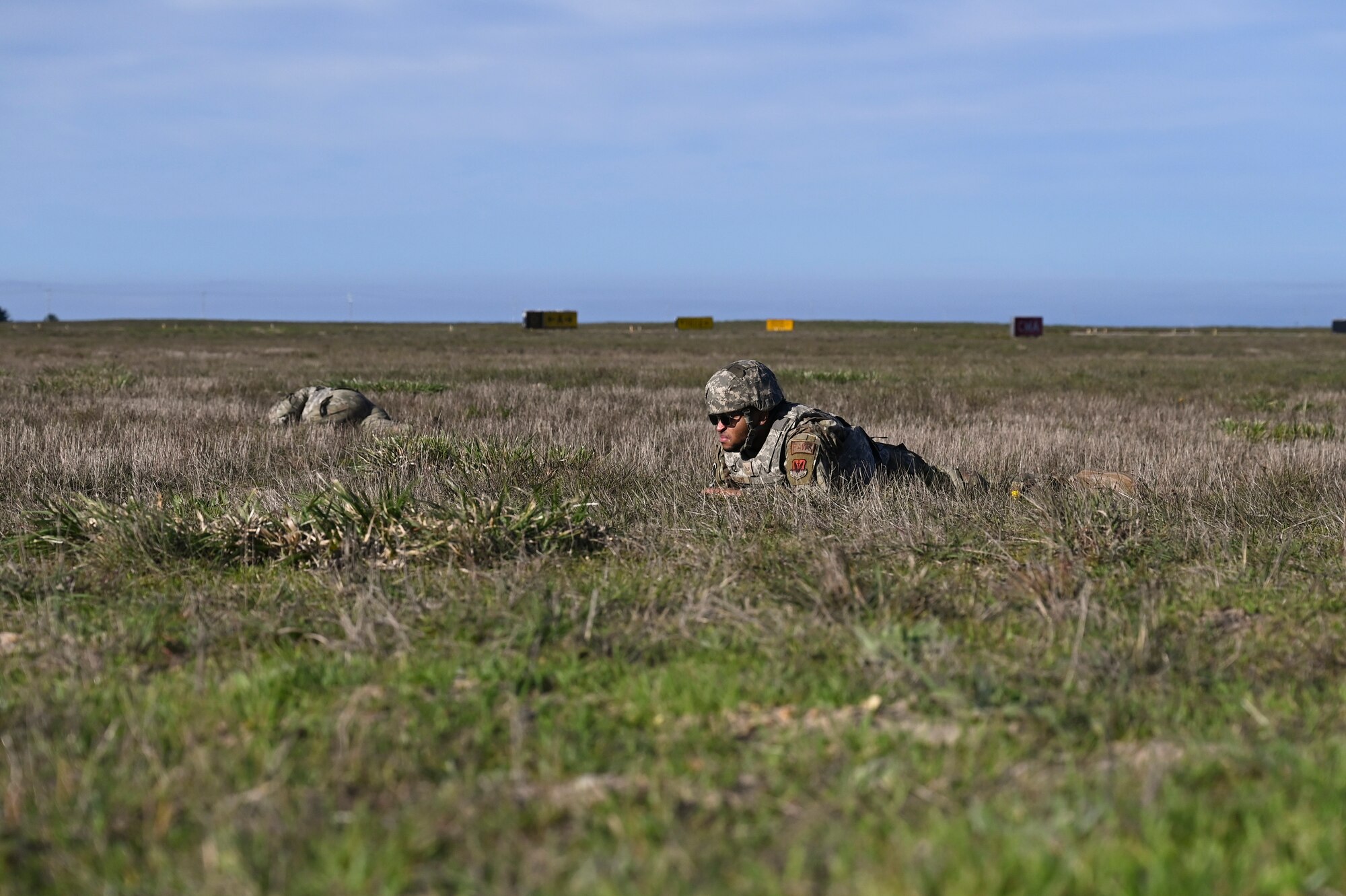 Two Air Force members lay in the grass at Vandenberg during an exercise.