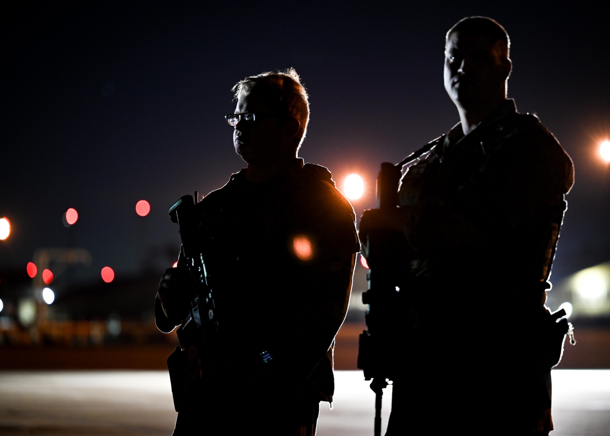 Security forces Airmen patrol the flightline at night.