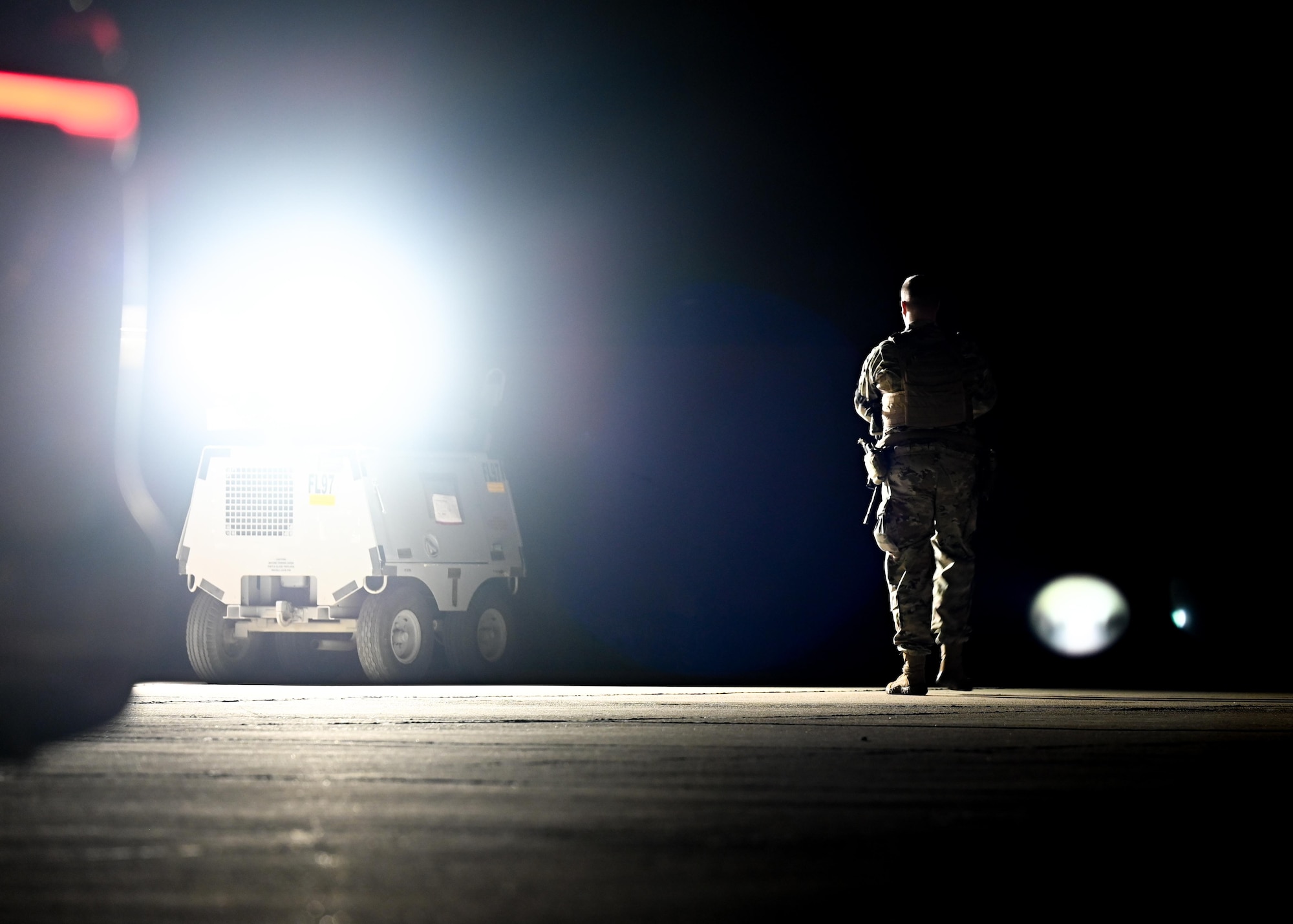A security forces Airman patrols the flightline at night.