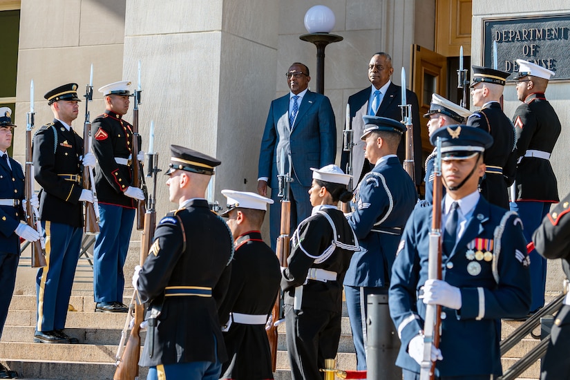 Two civilians stand at the top of a staircase with service members on each side.