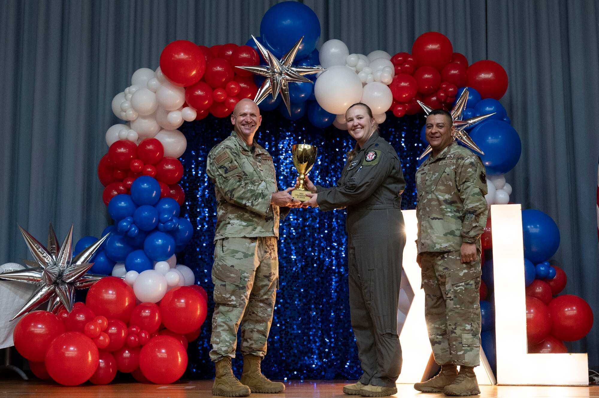 U.S. Air Force Col. Kevin Davidson, 47th Flying Training Wing (FTW) commander, and Chief Master Sgt. Lester Largaespada, 47th FTW command chief, present Lt. Col. Elizabeth Music, 47th Student Squadron commander, the 2023 Intramural Commander’s Trophy during the 2023 47th FTW Annual Awards Ceremony at Laughlin Air Force Base, Texas, Feb. 2, 2024. The annual awards recognized the top performers throughout the 47th Flying Training Wing during fiscal year 2023. (U.S. Air Force photo by Senior Airman Kailee Reynolds)