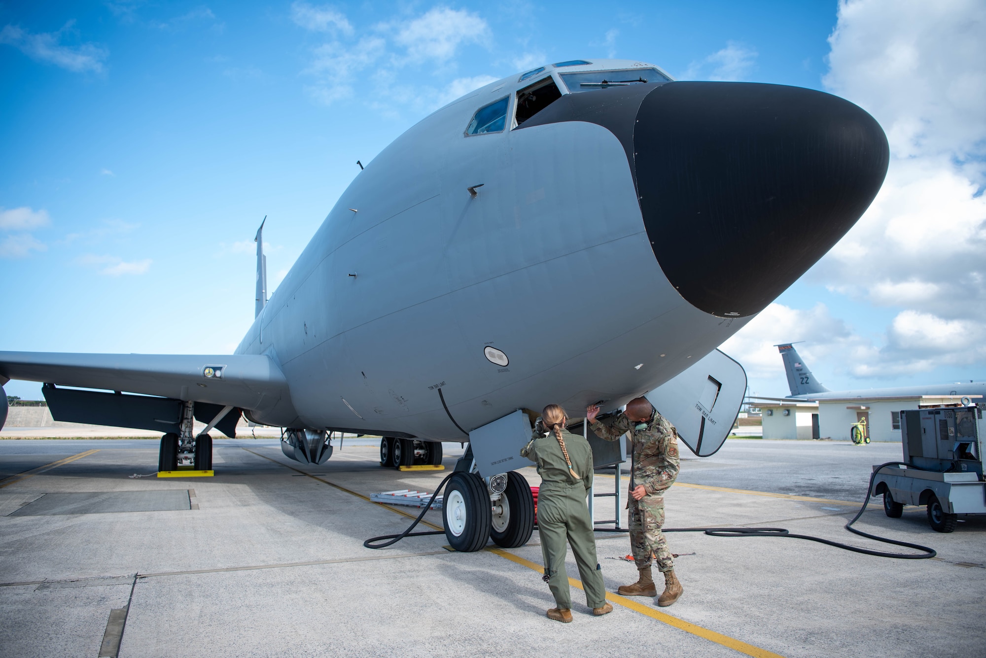 airmen stand underneath a plane checking before a flight