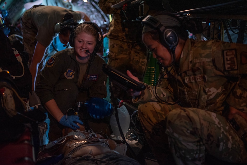 two medical airmen give oxygen to a manikin