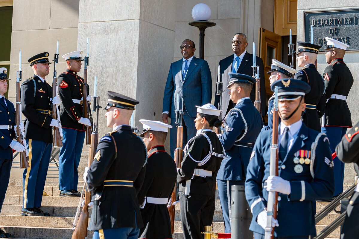 Two civilians stand at the top of a staircase with service members on each side.