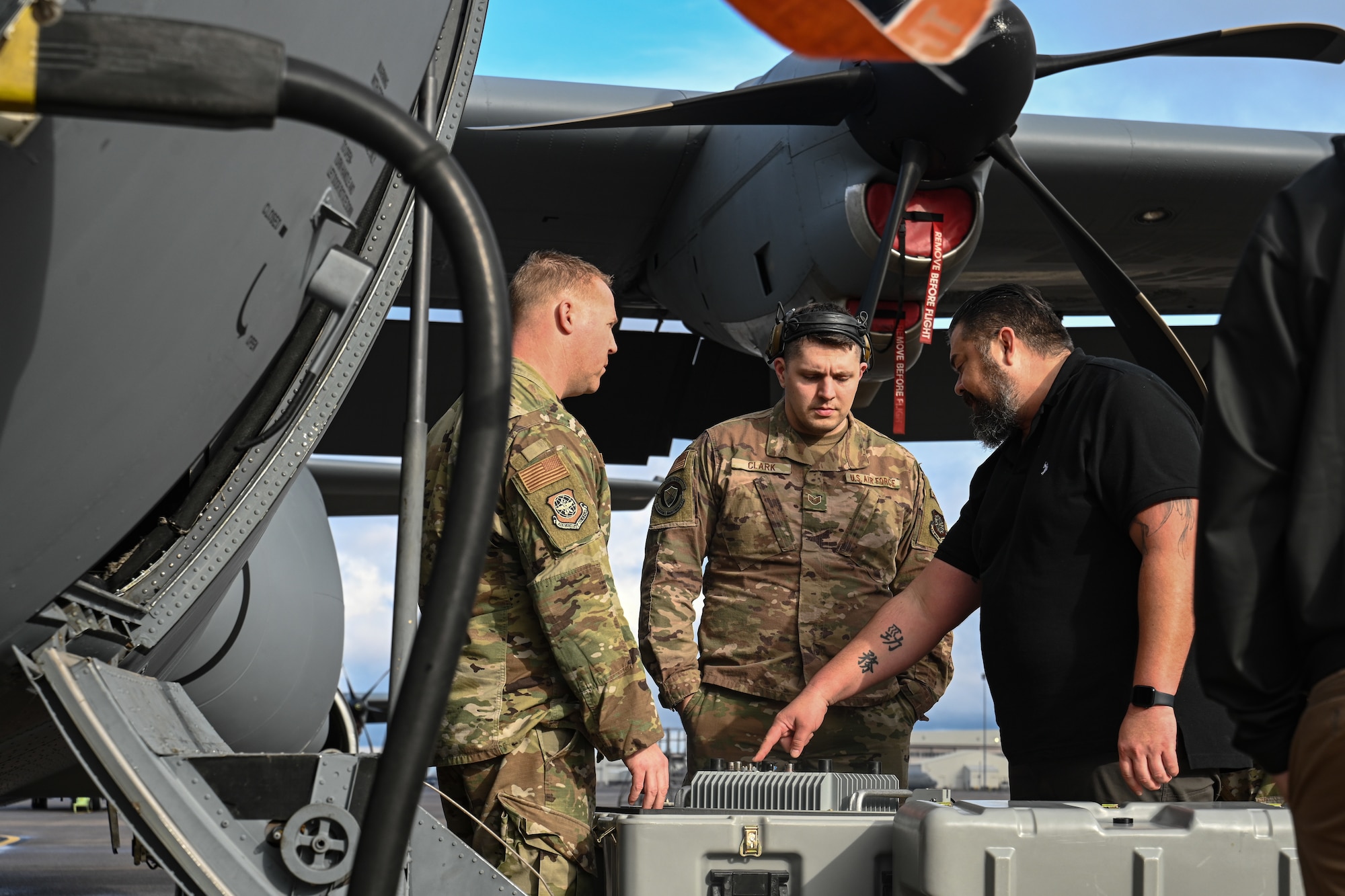 Airmen and man explore a satellite communication suite.