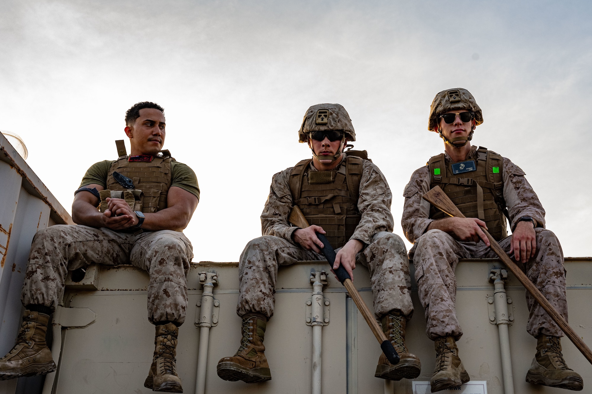 U.S. Marines sit on the edge of a shipping container with individual protective equipment and dummy weapons.