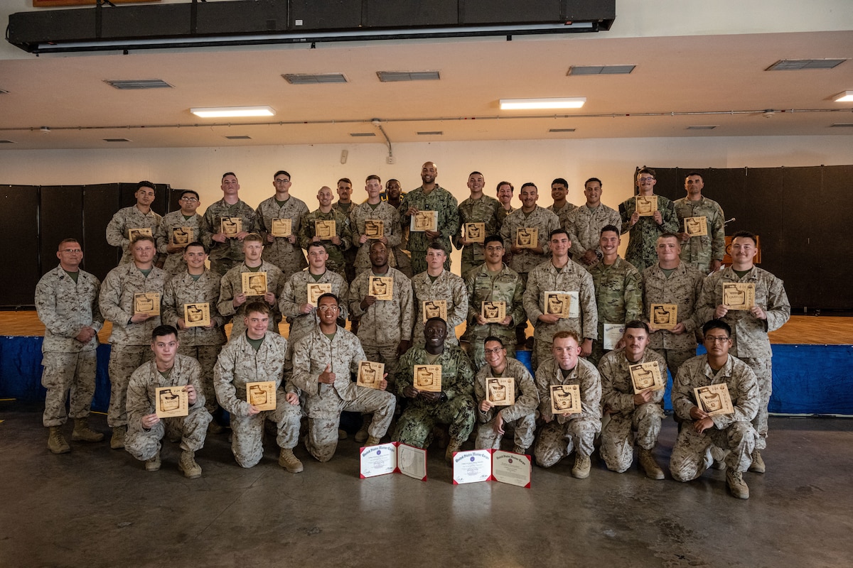 A group photo showing Corporals Course graduates holding their graduation certificates.