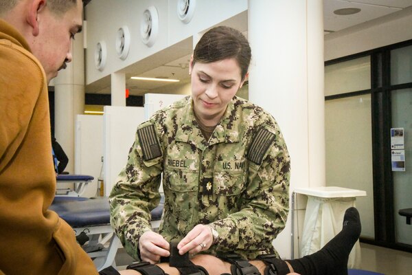 Lcdr. Laura Riebel adjusts a leg brace during a physical therapy session. Riebel was awarded the Navy Medicine Senior Physical Therapy Officer of the Year for 2023