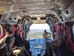 U.S. Soldiers, U.S. Airmen, and a Department of Defense civilian ride in the back of a Chinook helicopter to observe training activities during the Maple Thunder exercise in Savannah, Georgia, Jan. 29, 2024.