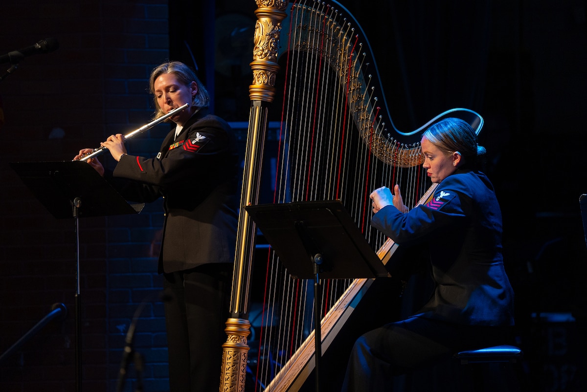 Navy Petty Officers 1st Class Ashleigh Leas and Madeline Jarzembak, members of the U.S. Navy Band, perform a flute and harp duet for students at Meyerland Performing and Visual Arts Middle School in Houston, Feb. 2, 2024.
