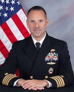 A portrait of CAPT Onofrio P. Margioni seated in front of an American Flag