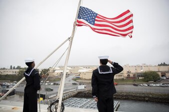 Sailors lower the national ensign aboard USS Abraham Lincoln (CVN 72) at Naval Base San Diego.