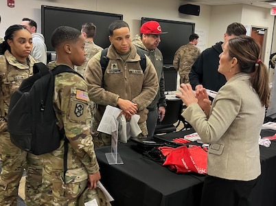 Men and women wearing u.s. army uniforms talk to people standing people from a university.