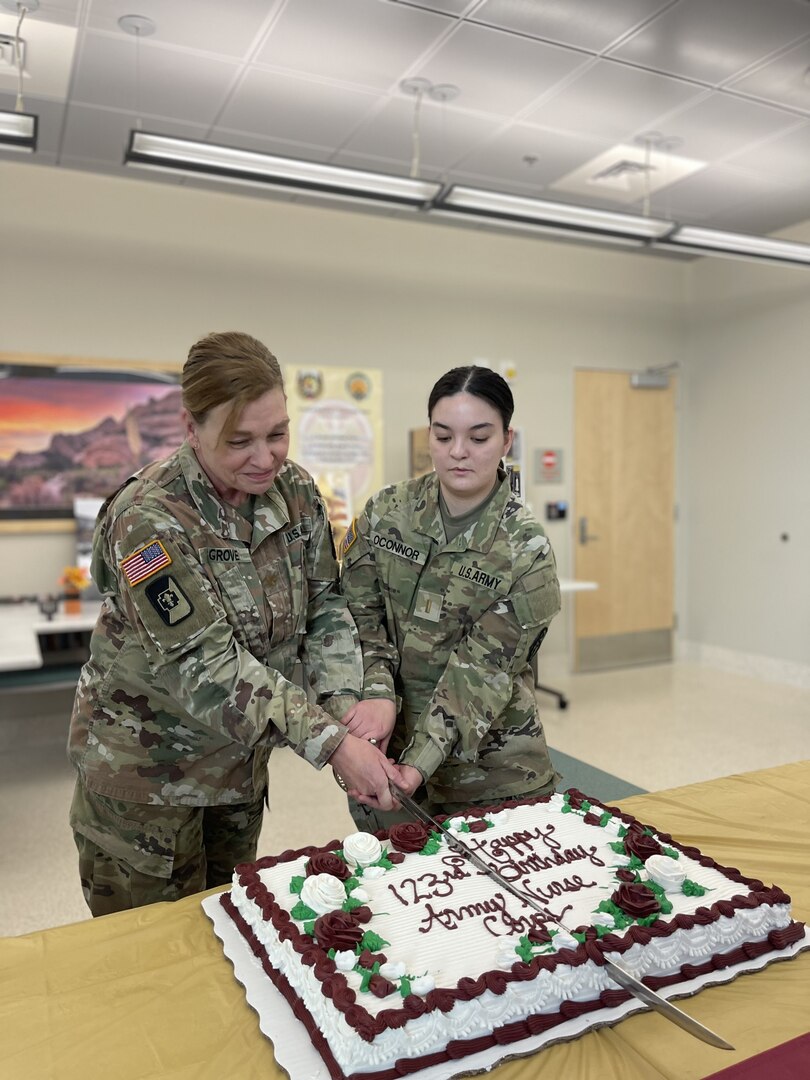 Army nurses cut cake at Nurse Corps birthday celebration.