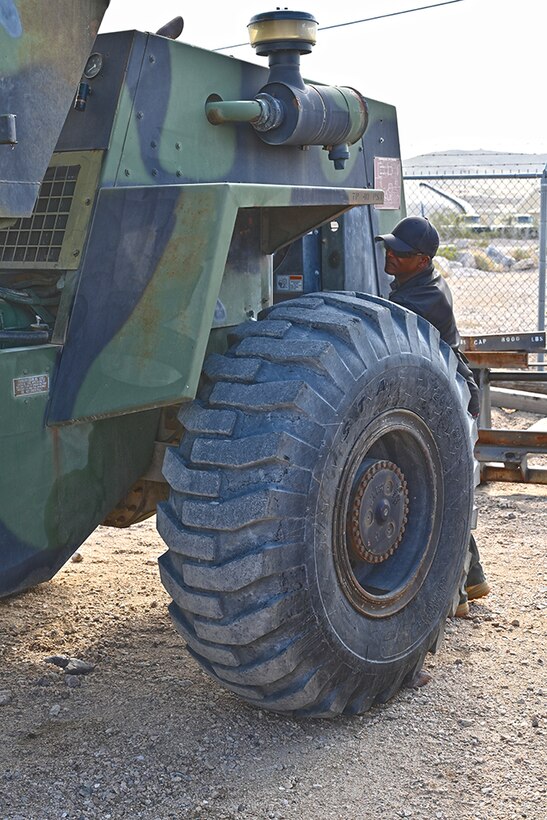 A man performs maintenance on a front-end loader.