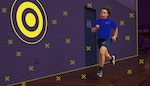 Graphic image of a service member running. A purple wall is in the background with a door that says "Not an exit" and a graphic image of a target.