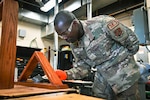 Senior Airman Ebrima Minteh, structural journeyman with the 155th Civil Engineer Squadron, stains a shadowbox display case Feb. 2, 2024, at the National Guard air base in Lincoln, Nebraska. Minteh, originally from The Gambia, joined the Nebraska Air National Guard in 2021 after receiving his degree from the University of Nebraska Omaha and obtaining his five-year green card.