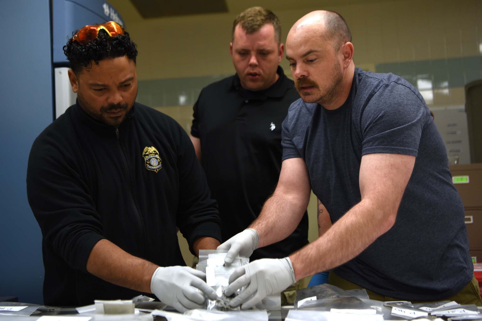 Mr. Carlos Colon, left, U.S. Army Sgt. First Class Earnie Williams, center, and U.S. Air Force Maj. Anthony Vinson, right, catalogue remains found during Operation Colony Glacier, June 23, 2023, at Joint Base Elmendorf-Richardson, Alaska. The operation aims at recovering and returning the remains of service members and personal effects from a C-124 aircraft that crash landed in 1952 with 52 souls on board. Staff from the Armed Forces Medical Examiner System have directly participated in these efforts since 2017. (U.S. Air Force photo by Staff Sgt. Deven Schultz)