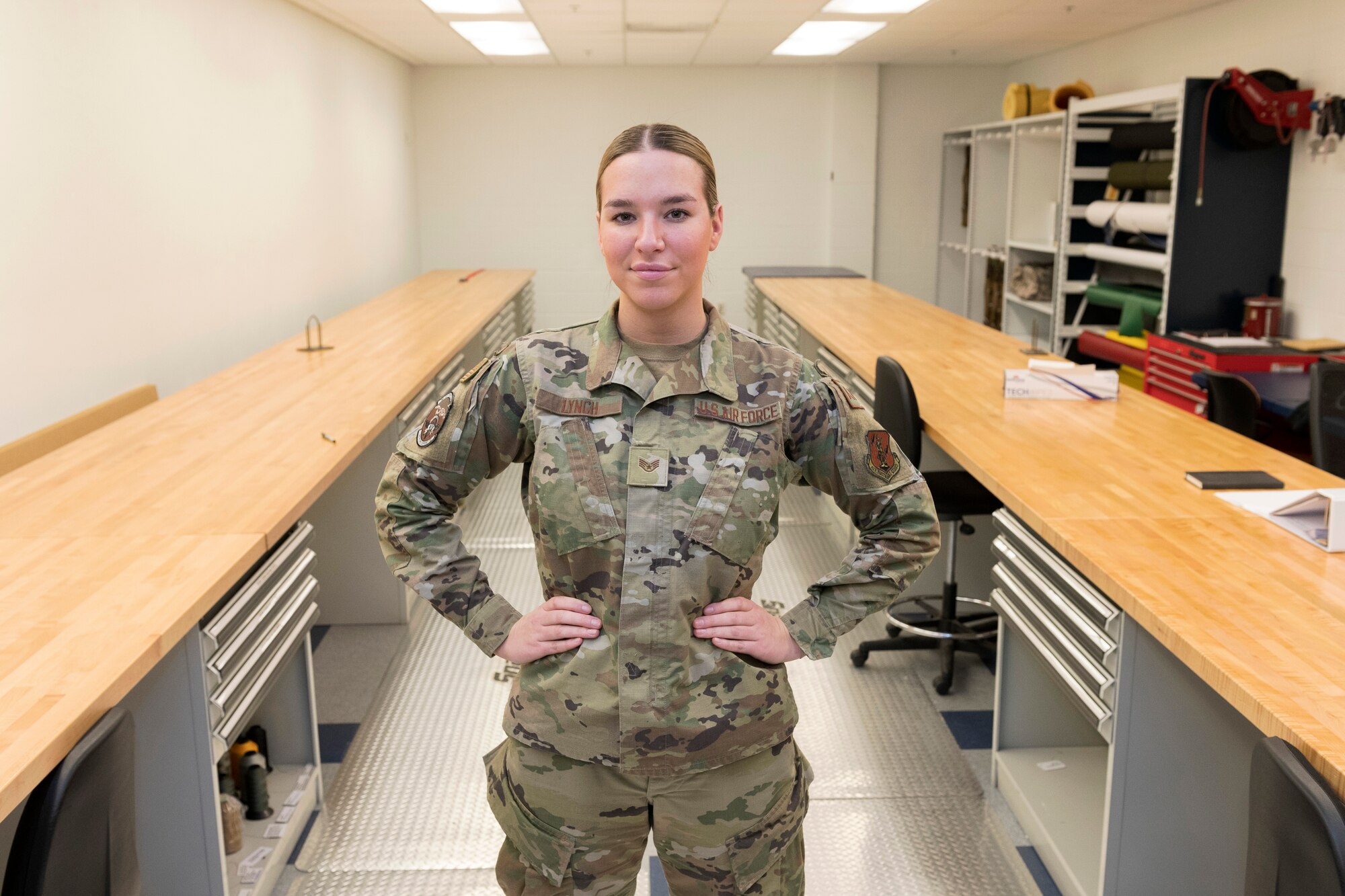 Woman in uniform stand with hands on hips in between two long tables