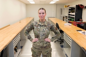 Woman in uniform stand with hands on hips in between two long tables