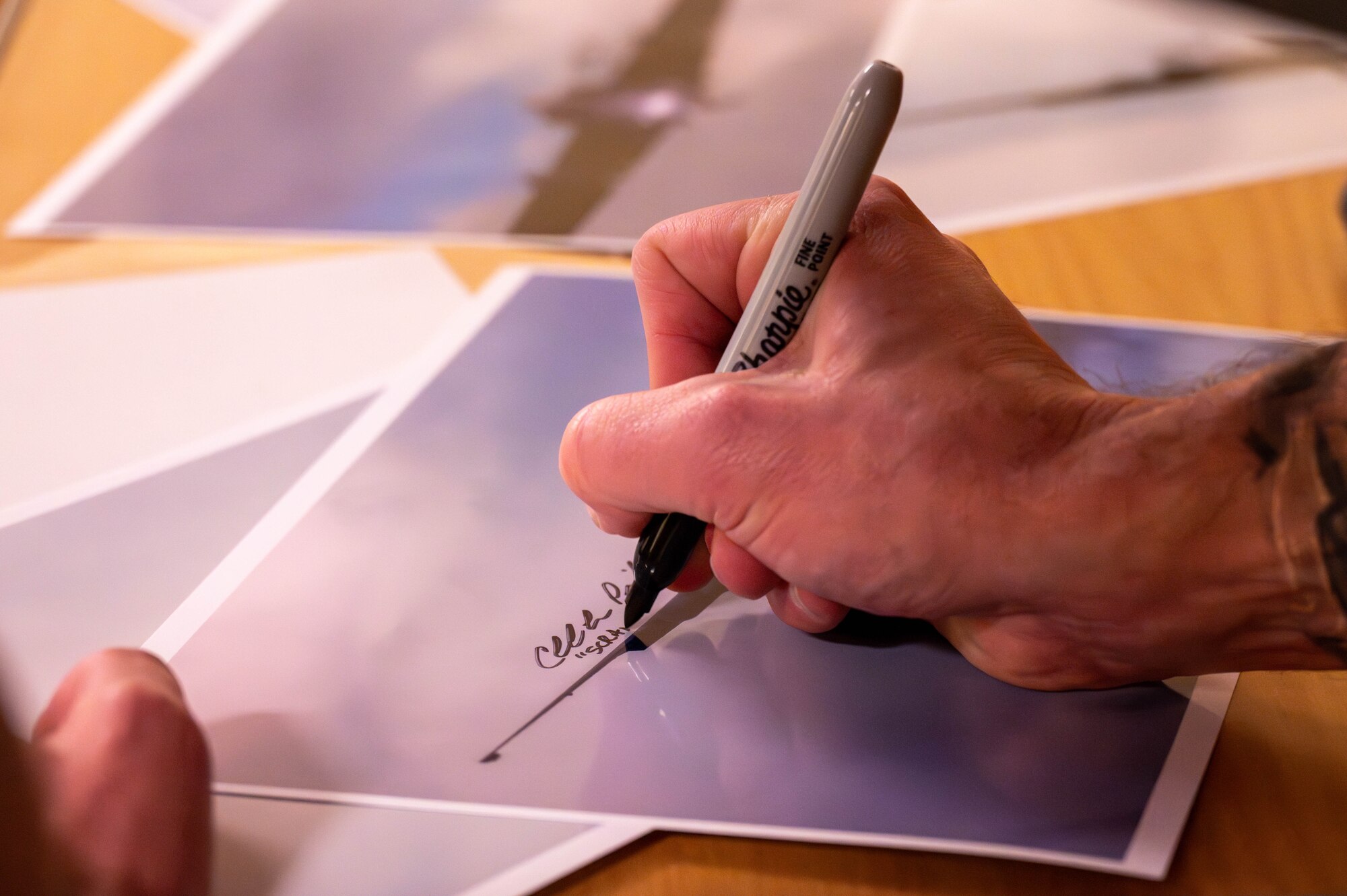 A member of the 99th Expeditionary Reconnaissance Squadron signs a photo.