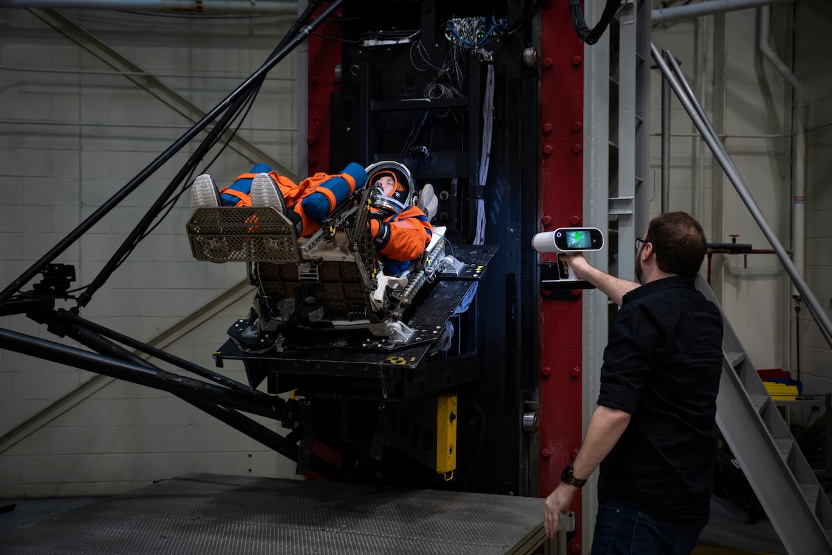 Max Grattan, right, Biodynamics Laboratory technical support contractor with Infoscitex, conducts 3D surface scanning of a U.S. Air Force volunteer on the horizontal sled test facility at Wright-Patterson Air Force Base, Ohio, Nov. 3, 2023, to test the next replica of a seat and flight suit for the Orion space capsule. Researchers with the AFRL Human Effectiveness Directorate tested equipment for the Orion space capsule’s upcoming mission to the moon. (U.S. Air Force photo / Richard Eldridge)