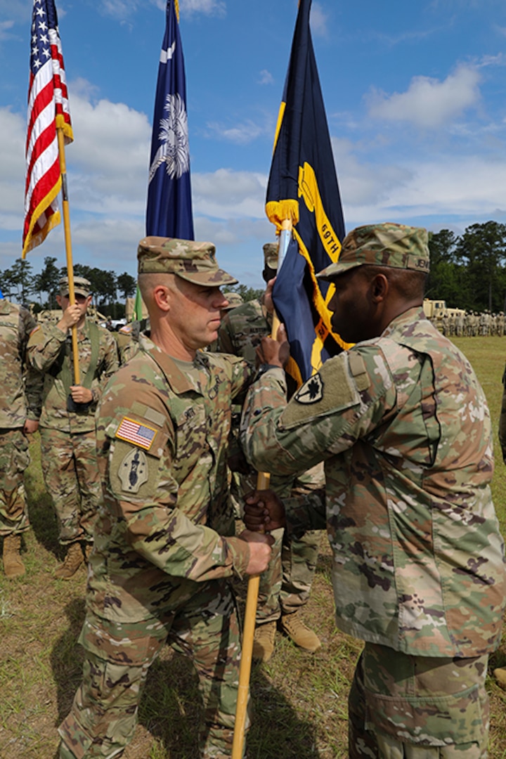U.S. Army Brig. Gen. David Jenkins, land component commander, South Carolina Army National Guard, passes the unit colors to Lt. Col. Denton W. Smith Jr., incoming 59th Troop Command commander, during a change of command ceremony at McEntire Joint National Guard Base in Eastover, South Carolina, June 4, 2023.