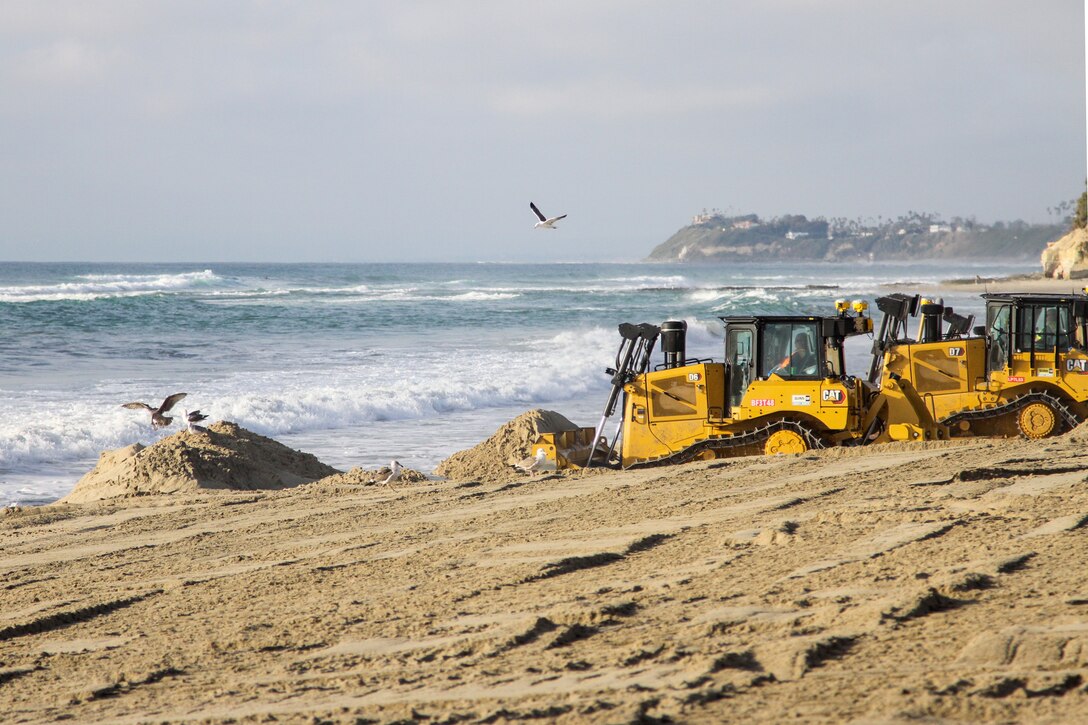 Contractors operating bulldozers move freshly dredged sand into place Jan. 31 at Solana Beach, California.