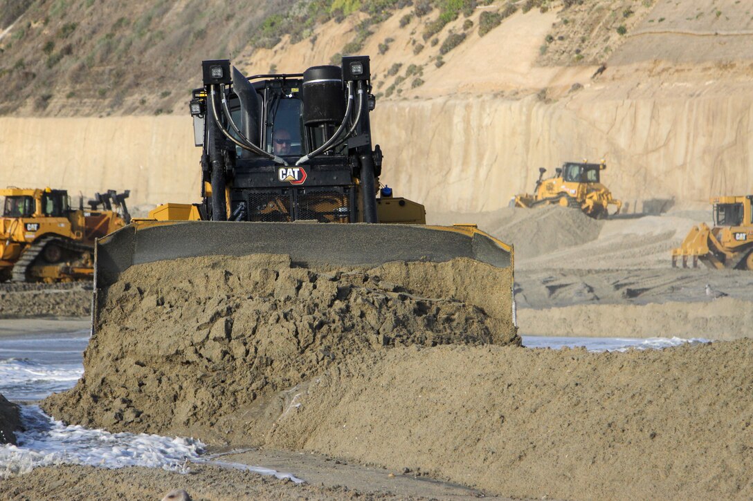 Contractors operating bulldozers move freshly dredged sand into place Jan. 31 at Solana Beach, California.