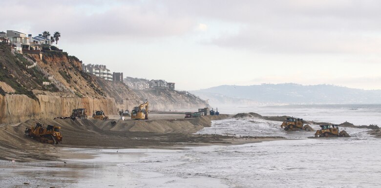 Contractors operating bulldozers move freshly dredged sand into place Jan. 31 at Solana Beach, California.