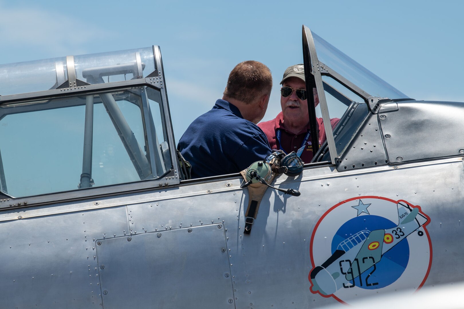 Retired Col. Robert Prater, a former 137th Special Operations Wing Guardsman, shows 137th SOW Command Chief Master Sgt. Lawrence DeSalle, left, his T-6G Texan aircraft at the Tinker Air Show on July 1, 2023, at Tinker Air Force Base, Oklahoma City. Prater has been flying World War II-style aircraft for over 20 years and shares military history with future generations. (U.S. Air National Guard photo by Airman 1st Class Erika Chapa)
