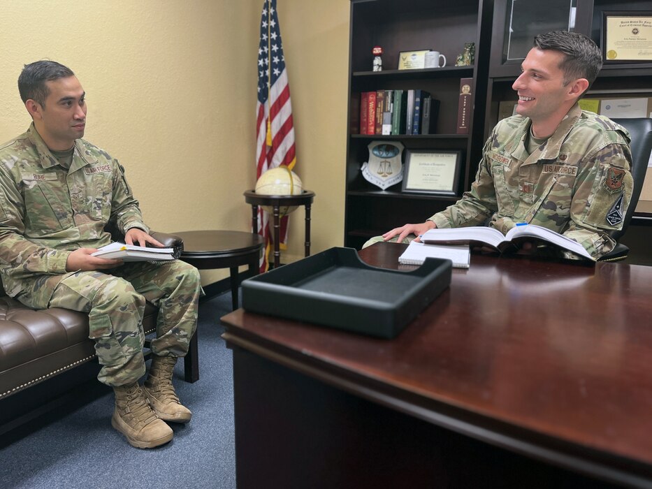 Two Air Force members in uniform are conferring on a legal case.