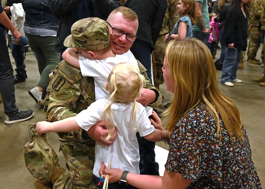 From left, Staff Sgt. Larry Davis reunites with his children, Parker and Camryn, and wife, Samantha, during a 3-197th Field Artillery Regiment welcome home ceremony Feb. 8 at the Manchester armory. About 370 soldiers, including a battery of 84 guardsmen from Michigan, deployed last spring to the Middle East. The New Hampshire Army National Guard HIMARS (high mobility rocket system) battalion completed a nine-month rotation in support of Operations Spartan Shield and Inherent Resolve.