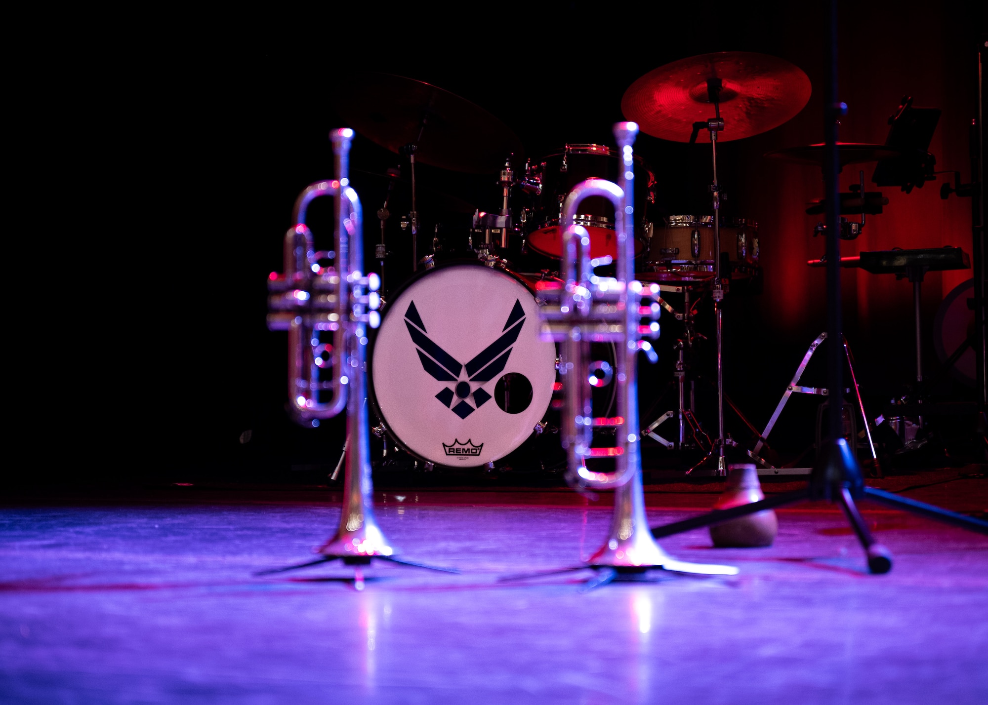 A drum set and two trumpets sit on stage