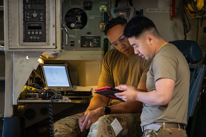 Two Airmen conduct pre-flight checks.