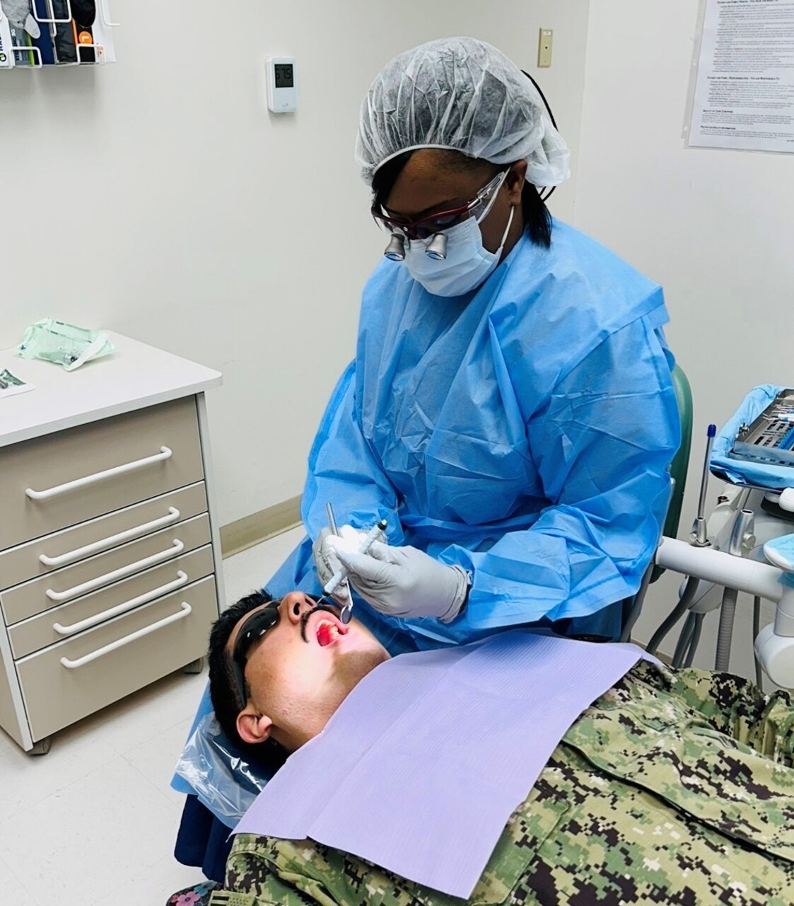 Donisha Williams, a dental hygienist at Naval Branch Health Clinic Albany Dental Clinic, inspects a patient’s mouth before performing a hygienic cleaning.