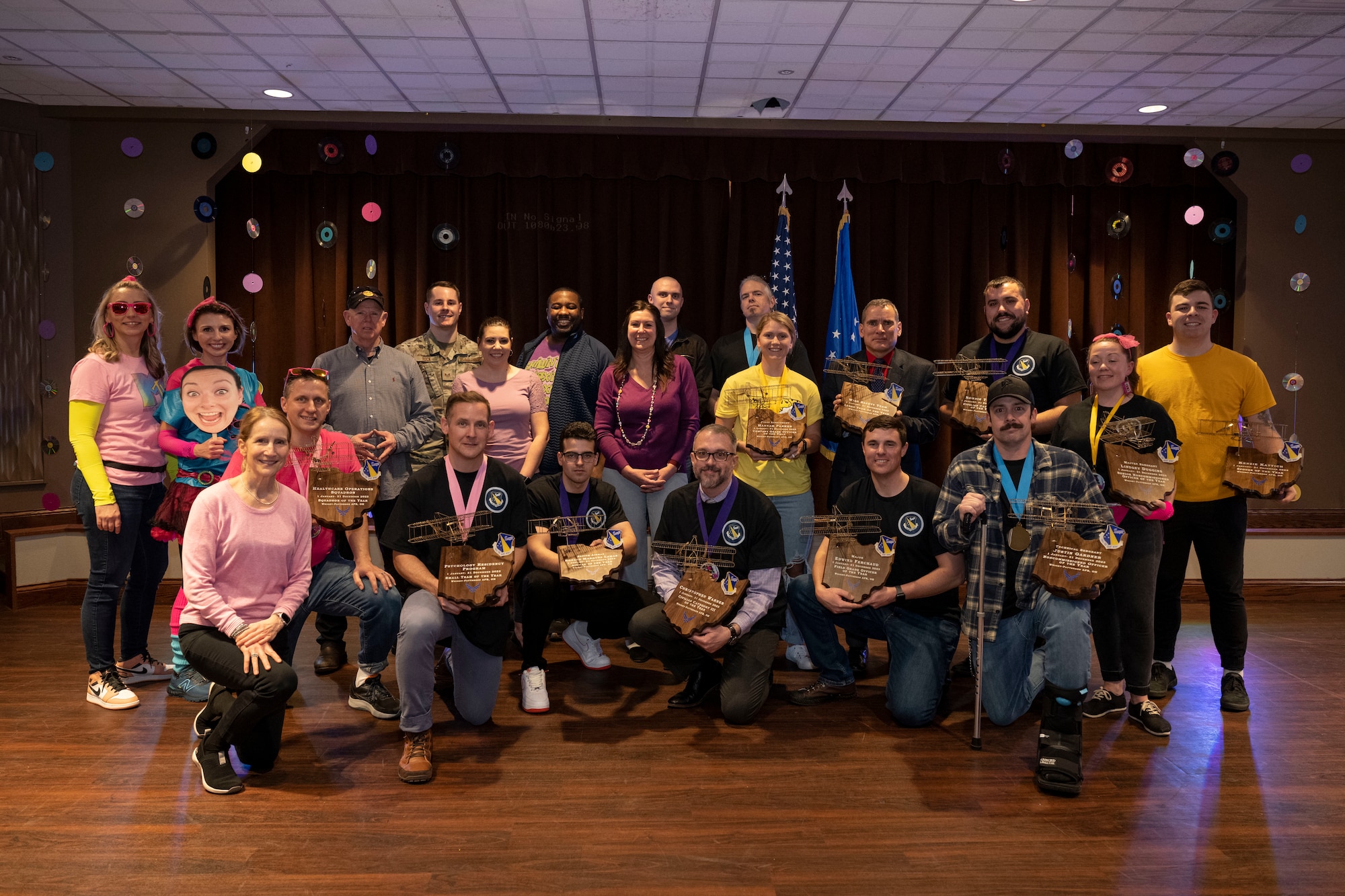 Winners hold plaque and dawn medallions for a group photo on the stage.